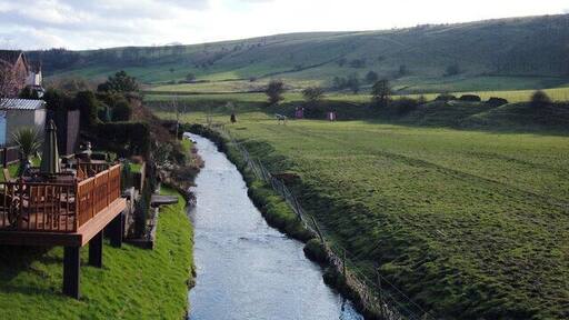 River Beal, Newhey Looking south from the bridge at the end of Bentgate Street. The rear gardens of houses on Whitebeam Close have been extended onto the river bank. The houses on the east bank are in Rochdale whilst the grazing land on the west bank is in Oldham. The ridge on the skyline carries the Rochdale Way, the Oldham Way and the Crompton Circuit footpaths.