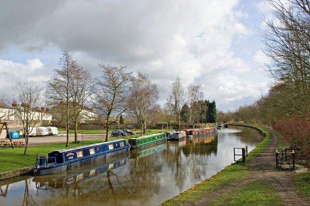 A canal with boats, trees, and a grassy bank.