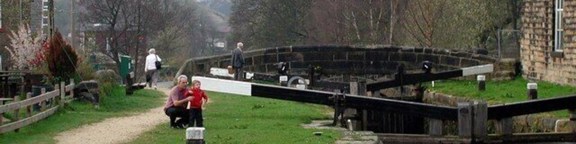Un canal con esclusas, un sendero cubierto de hierba y un edificio de piedra al fondo.