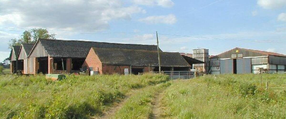 A rural farm with a large barn, a smaller building, and a silo.