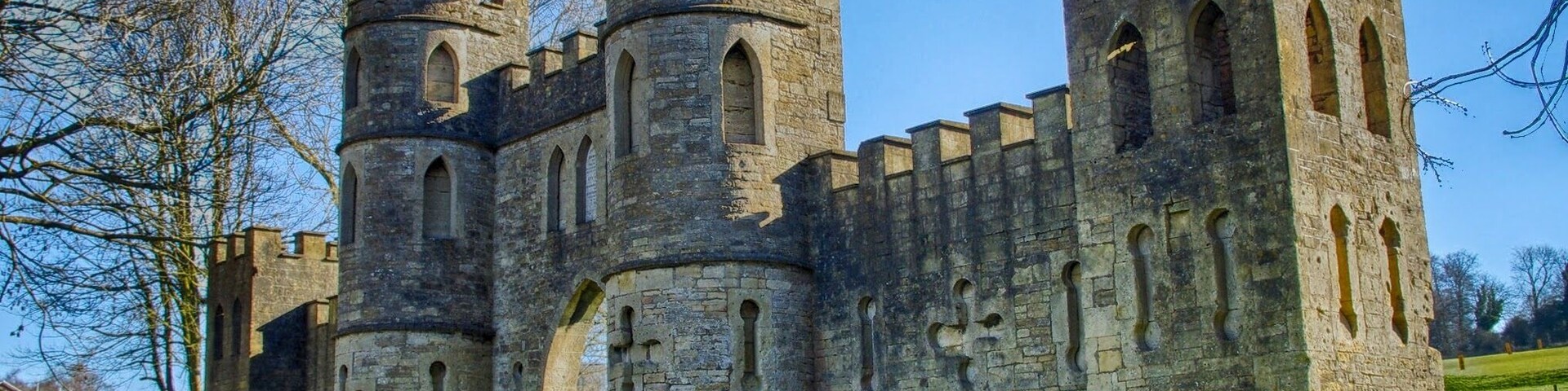 Um castelo de pedra histórico com múltiplas torres e janelas em arco.