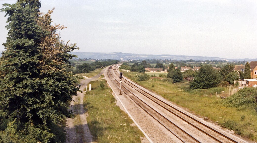 Site of Churchdown station, 1986. View NE, towards Cheltenham etc.: ex-GW & Midland Joint Gloucester etc. - Cheltenham etc. main line. This important line had been quadrupled for War traffic in 1942, but reverted to double-track in 1967. Churchdown station was closed from 2/11/64. (See also several other scenes, SO8820 : Cheltenham - Paddington express passing Churchdown station etc.).