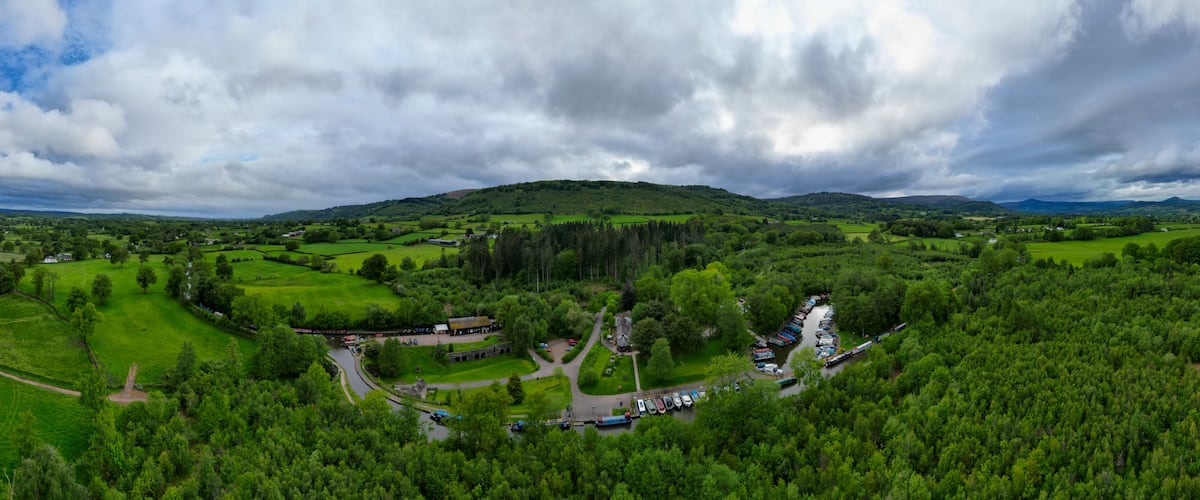 Un paisaje verde exuberante con colinas ondulantes, un río y un área de estacionamiento con botes.