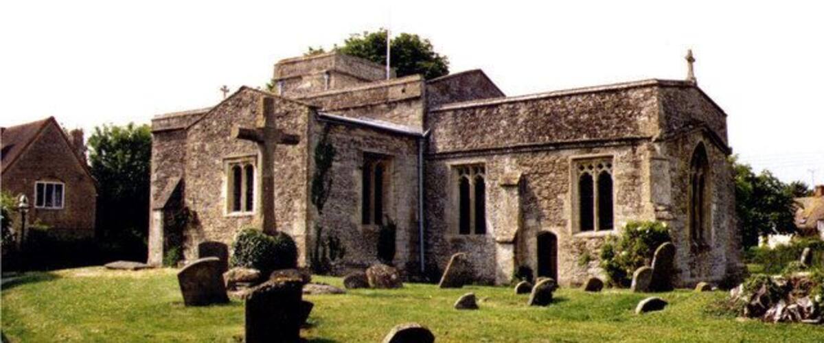 A stone church with a cross, surrounded by a cemetery with headstones.