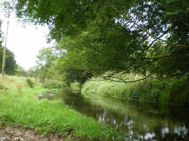 A calm river with lush greenery and trees along the banks.