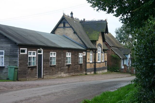 A wooden building with a sloped roof and a brick extension.