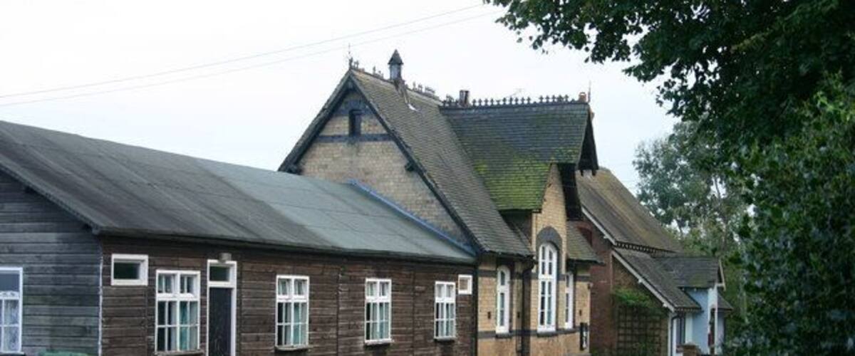 A wooden building with a sloped roof and a brick extension.