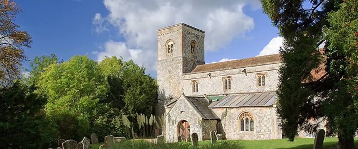 A historic church with a tower, surrounded by a cemetery with headstones.