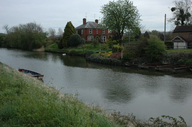 A calm river with a house and a boat on the left bank.
