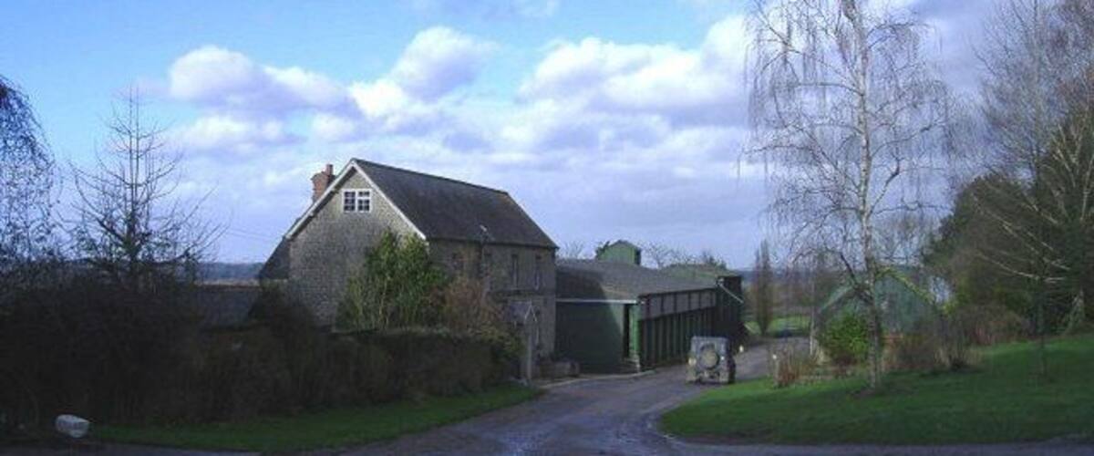 A rural road leading to a stone house and a barn.