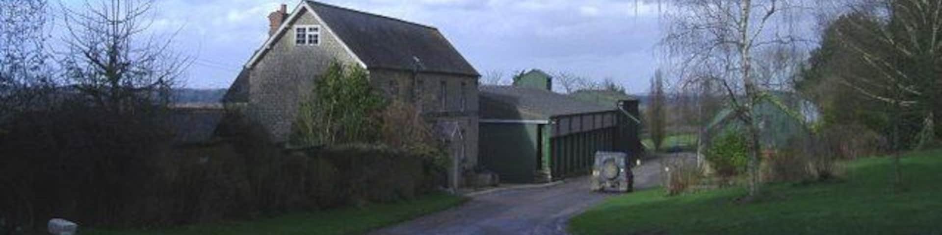A rural road leading to a stone house and a barn.