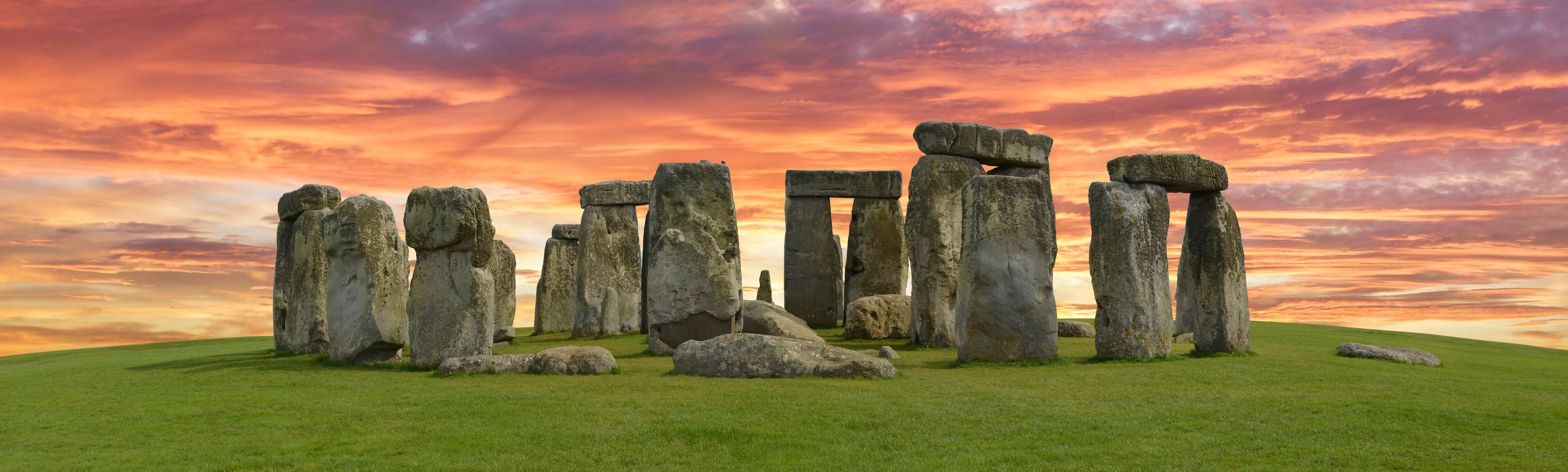 Stonehenge standing against a sunset sky.