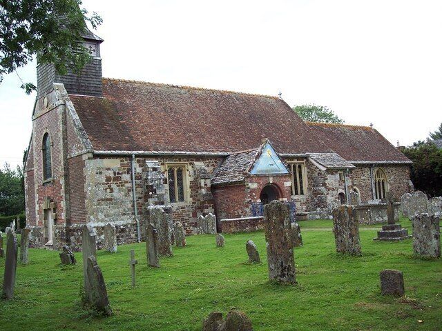 A church with a stone facade, a bell tower, and a grassy cemetery with headstones.