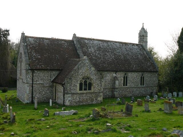 A stone church with a steeple, surrounded by a cemetery with headstones.