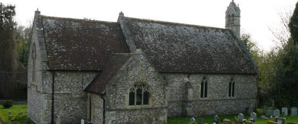 A stone church with a steeple, surrounded by a cemetery with headstones.