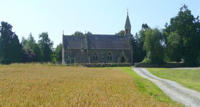 A church with a tall steeple, surrounded by a wheat field and a dirt road.