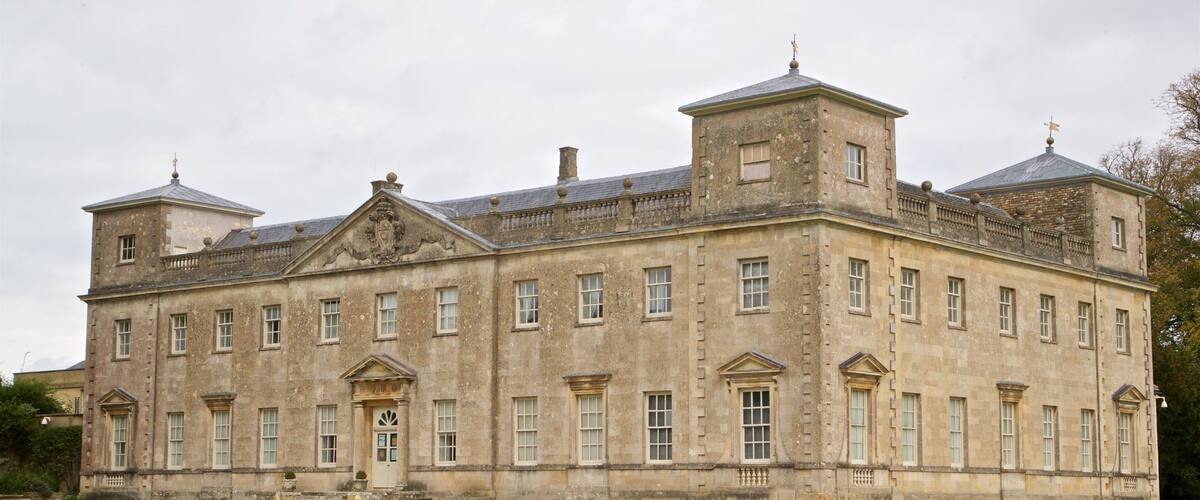 A large, historic stone building with multiple windows and a central entrance.