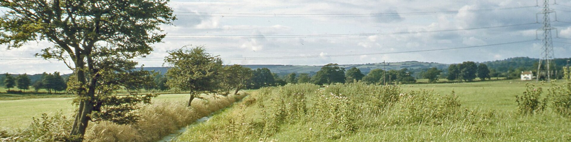 Northward along stream from near St Pierre Pill to Pill Cottage and towards Mathern. View northwards from beside the railway east of Portskewett station to the hills west of Chepstow. The railway is just behind and on its other side is the Severn Estuary.