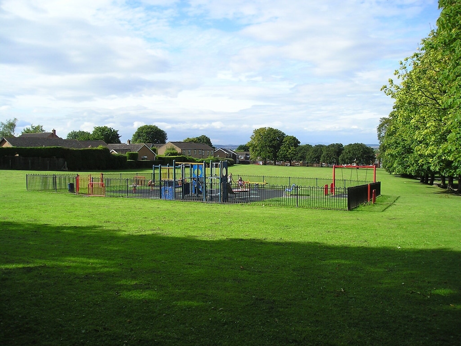 Un parque infantil con diversas estructuras de juego rodeado por una cerca.
