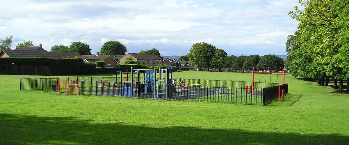 A playground with various play structures surrounded by a fence.
