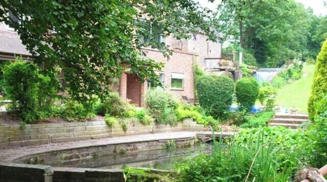 Moddershall Mill. A modern house stands downstream from the original mill which can be seen in the right background. The mill stream has been converted into an attractive water feature.