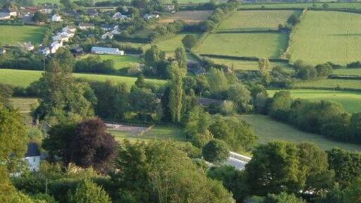 Northleigh from the northeast. From the top of the lane where a footpath joins it near Northleigh Cross, looking down across the village and the valleys that lead to the River Coly, towards Strap Common.