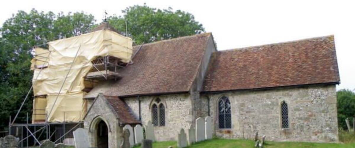 A church with a brick roof and stone walls, surrounded by a cemetery.