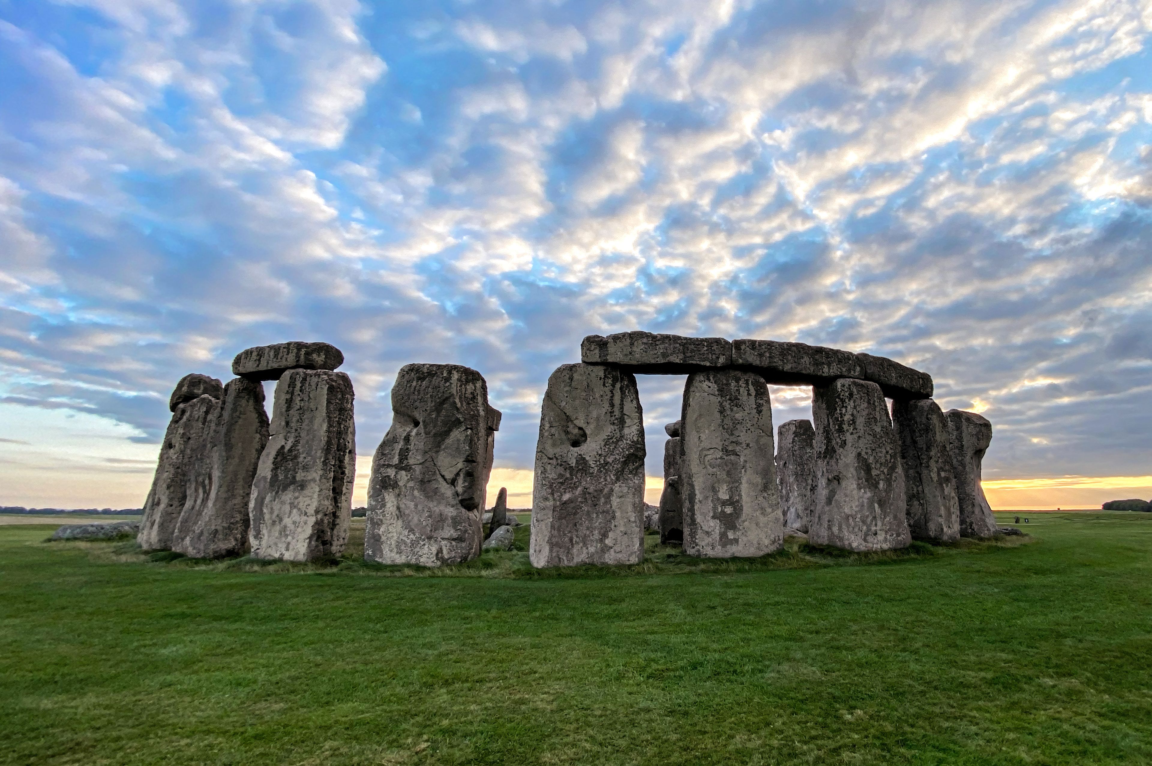 Stonehenge standing in a grassy field with a cloudy sky.
