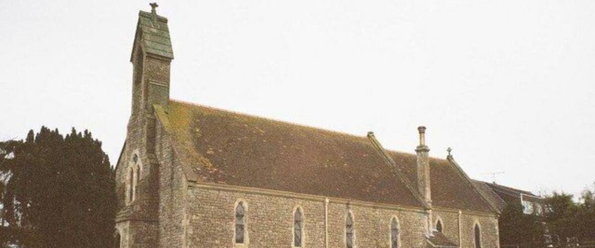 A church with a tall steeple and a graveyard in front.