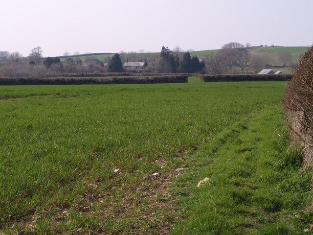Tuell The farm and associated buildings seen from a distance across fields, from a gateway beside Sydenham Damerel Footpath 1.