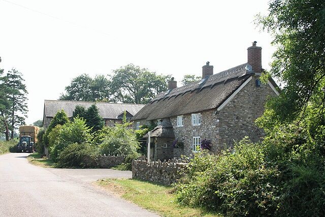 Upottery: Lambpark Farmhouse. A datestone by the porch, partially obscured by thatch, indicates that this building was erected in 1795 or 1796. All the buildings here are now residential: the farming function has ceased