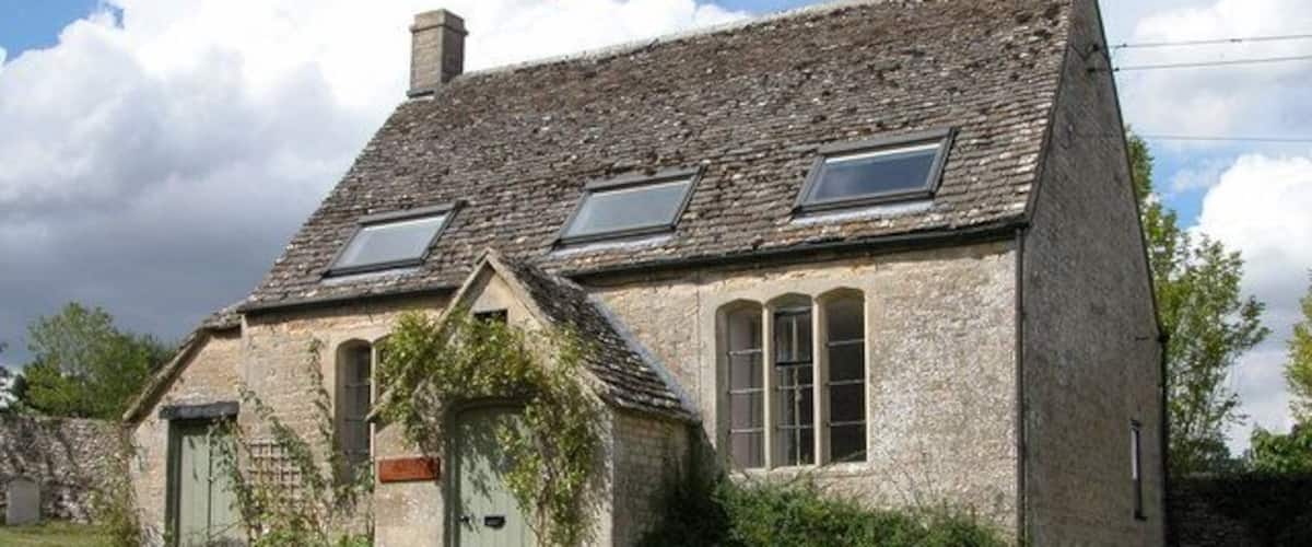 A stone house with a sloped roof, two skylights, and a green door.