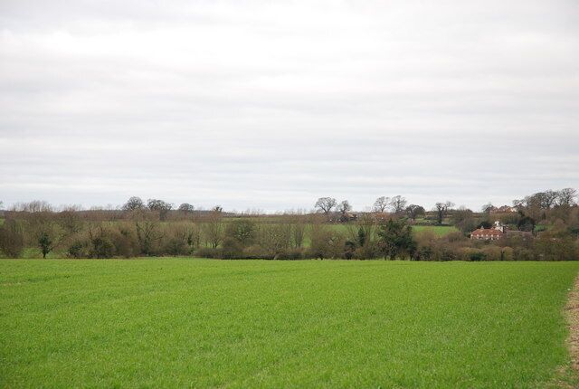 A green field with a distant building and trees.