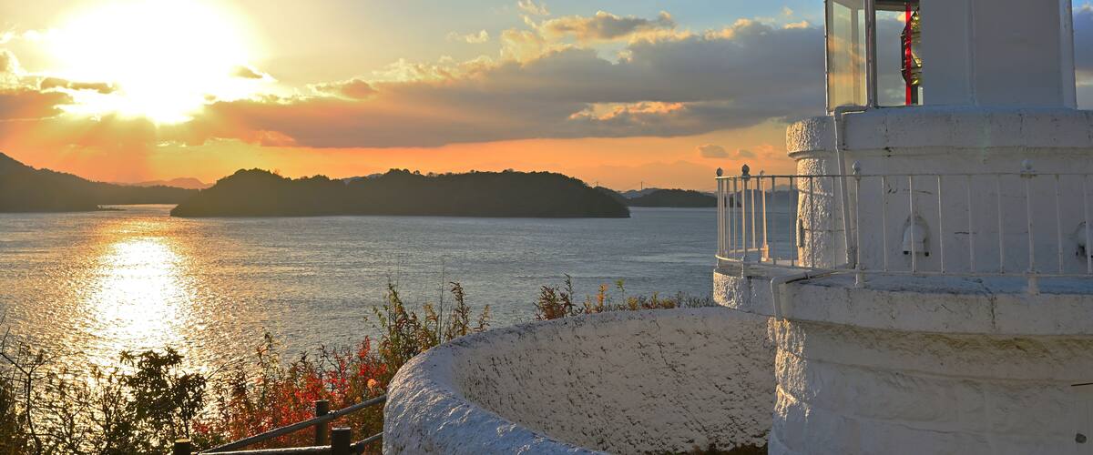 A lighthouse by a body of water during sunset.