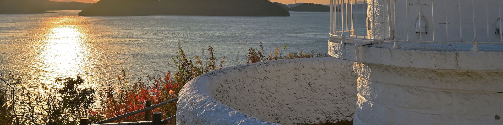 A lighthouse by a body of water during sunset.