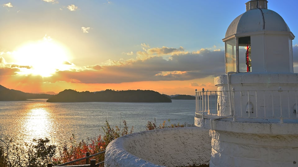 A lighthouse by a body of water during sunset.