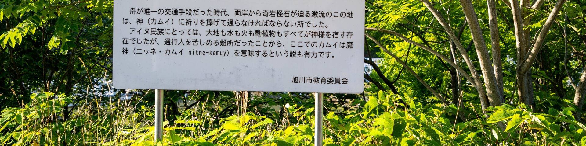 A signboard with Japanese text and a wooden fence in the foreground.