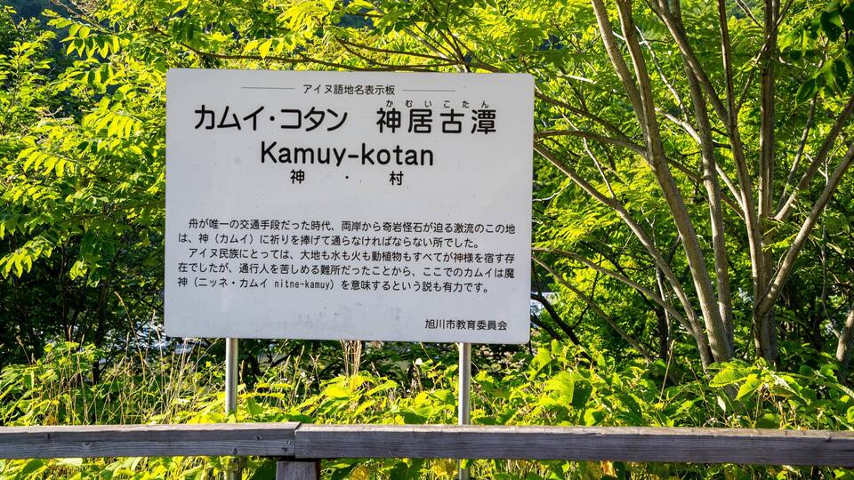 A signboard with Japanese text and a wooden fence in the foreground.