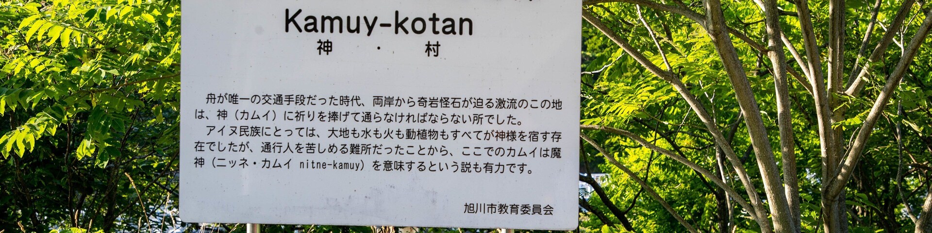 Un letrero con texto en japonés y una valla de madera al frente.