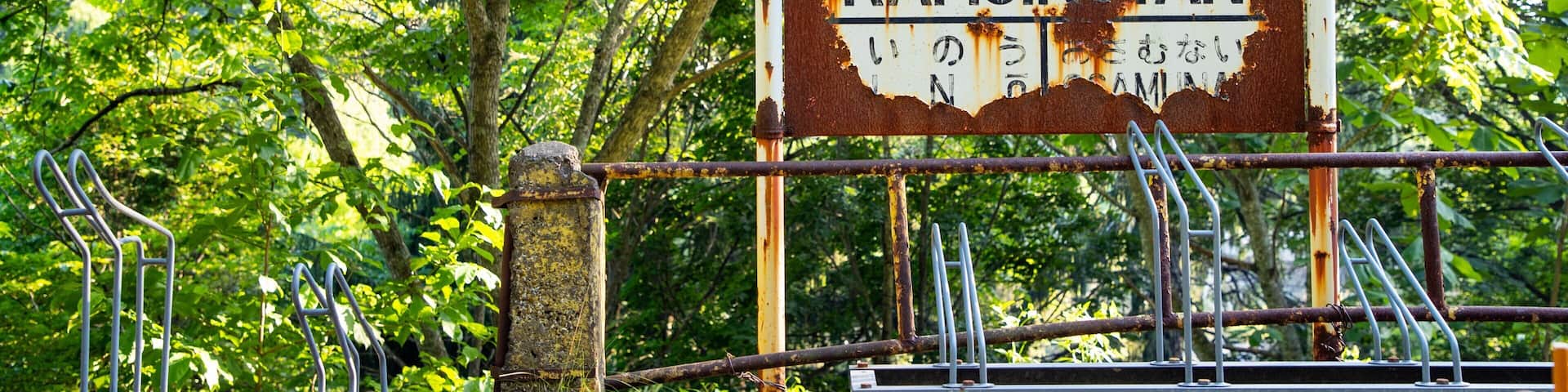 A weathered sign with Japanese characters and the word "KAMIKOTAN" in English, surrounded by lush greenery.