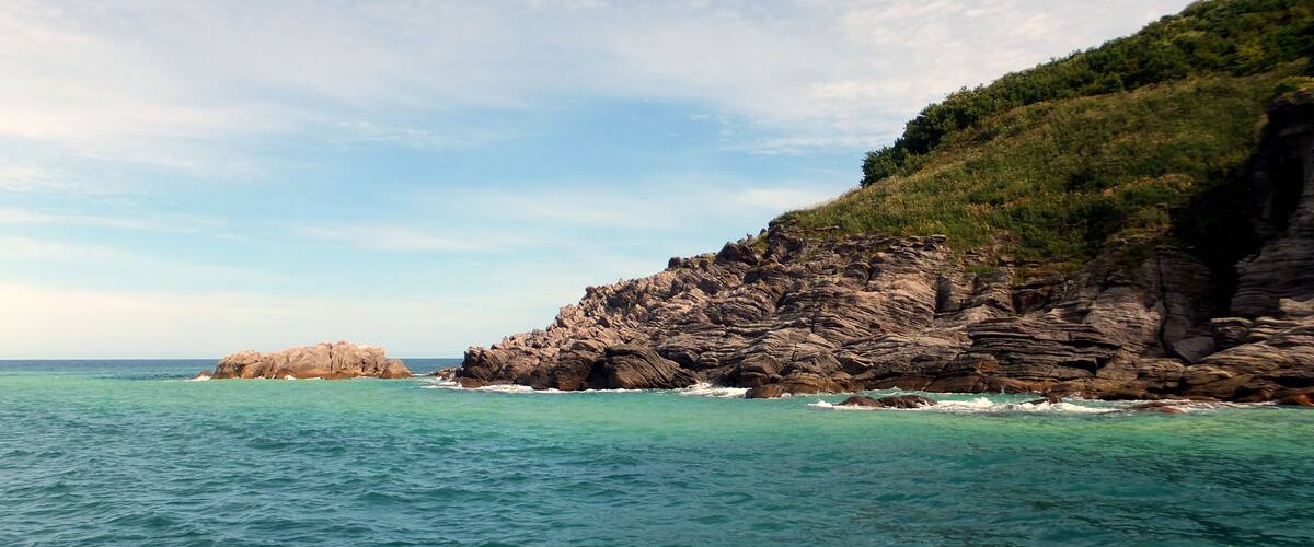 A coastal landscape with rocky cliffs and turquoise waters.