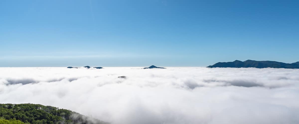 A mountain range above a sea of clouds with a clear sky.