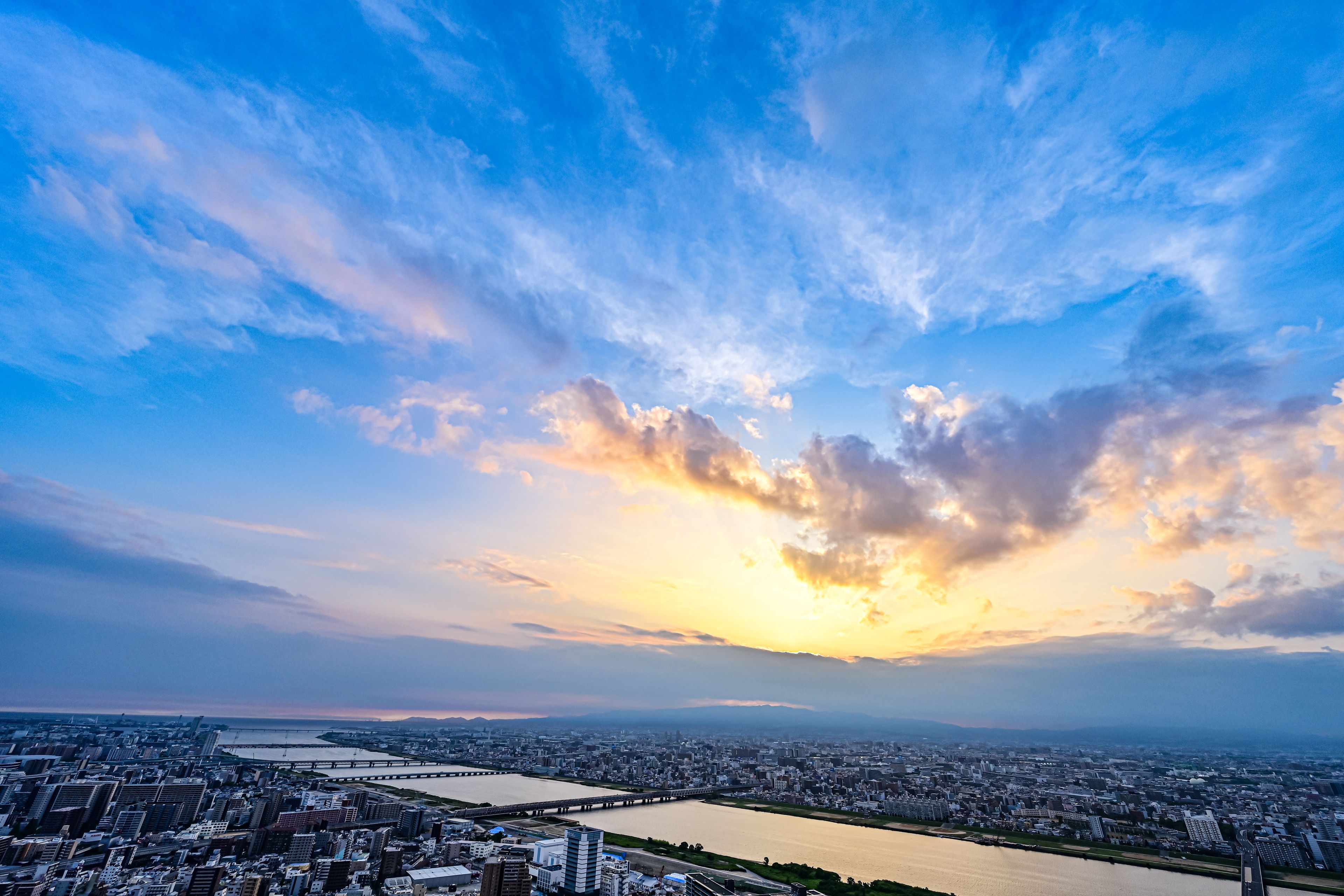 A cityscape with a river, bridges, and a sunset.