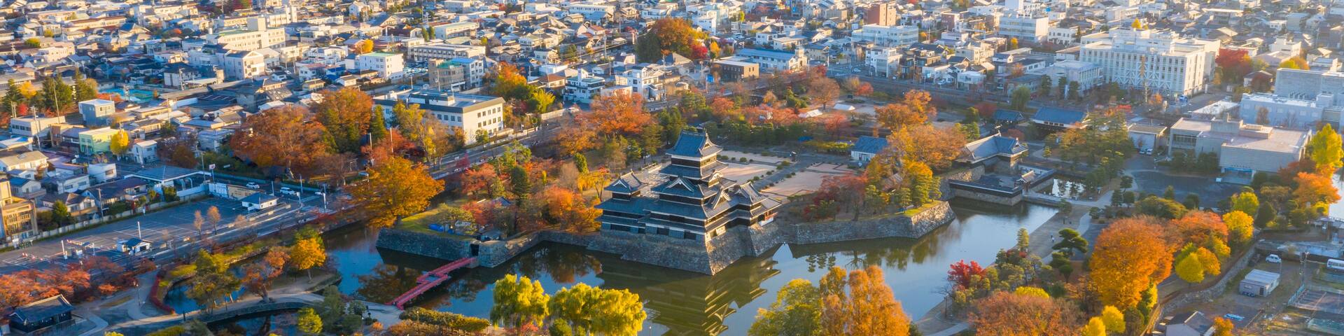 A cityscape with autumn foliage, traditional architecture, and a river.