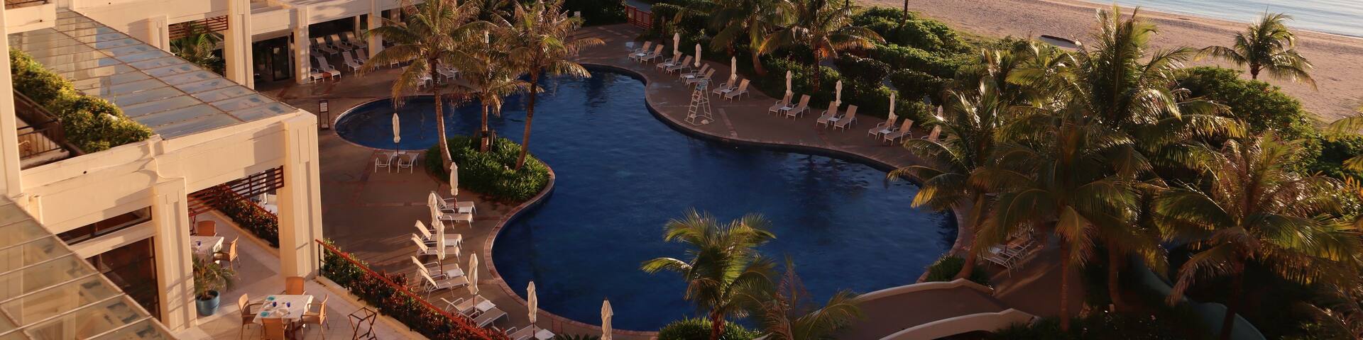 A resort with a swimming pool, beach, and ocean view.