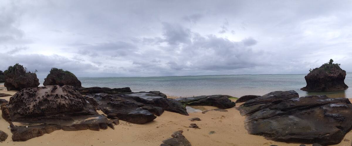 A beach with large rocks and a mountain in the background.