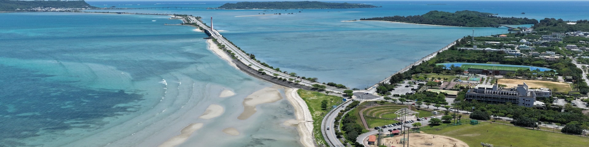 Paisagem costeira com uma ponte, uma praia e uma cidade.