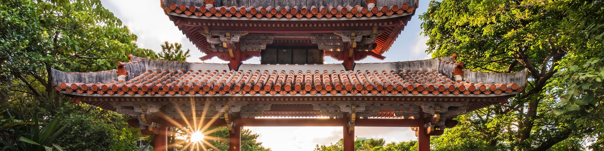 A traditional Chinese pavilion with a tiled roof, surrounded by lush greenery.