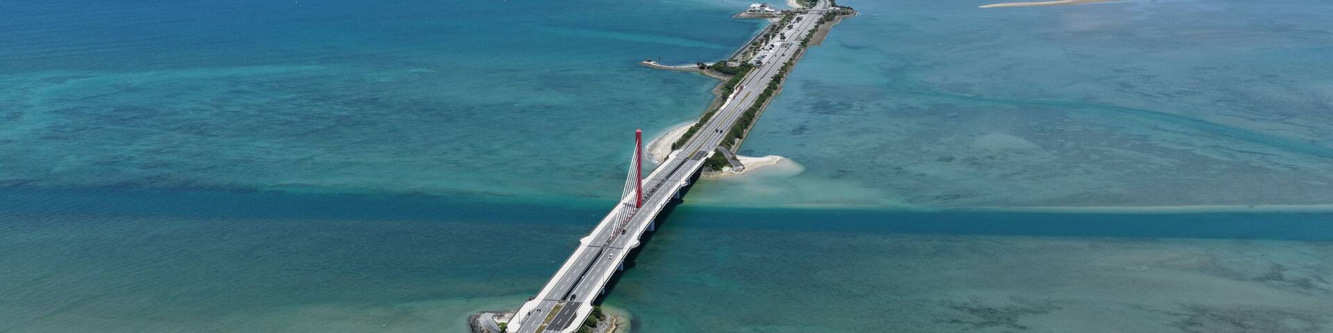 A long bridge spanning a body of water with clear blue water on both sides.