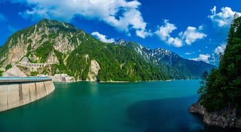 Panorama Beautiful scenery of Kurobe Dam on a brisk, with colorful lakeside mountains and crystal clear lake water under blue sunny sky in Tateyama Kurobe Alpine Route, Toyama, Japan
